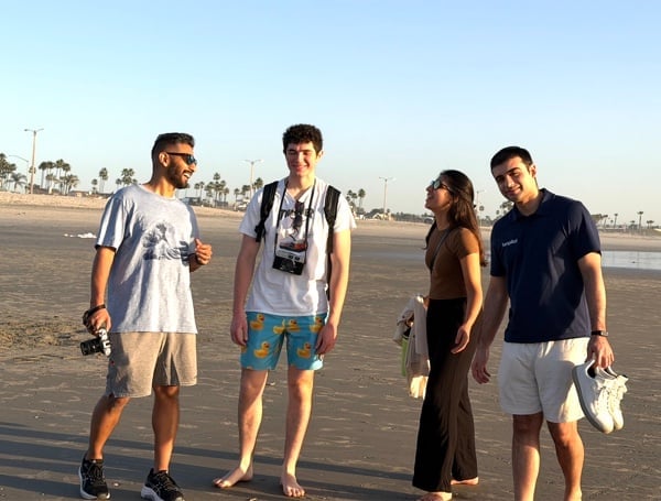 Four teammates talking and smiling on a beach